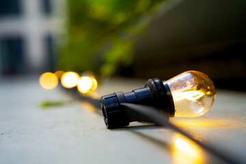 Lamp cord with LED lamps with warm white light. Party lights lying on the floor. Zoomed in on a single lamp.