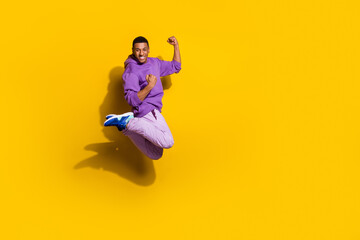 Obraz premium Full length body size view of attractive trendy cheerful guy jumping rejoicing win isolated on vivid yellow color background
