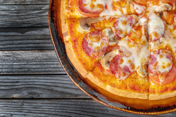 Slices of pizza with mushrooms, cheese and tomatoes on a wooden background. Vertical photo