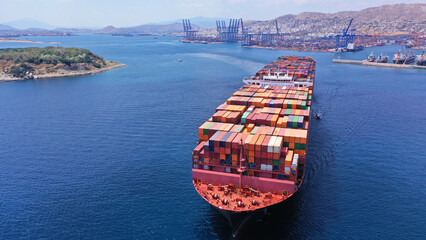 Aerial drone front view photo of huge container cargo ship leaving logistics and container terminal...