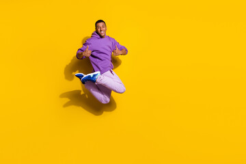 Fototapeta na wymiar Full length body size view of handsome trendy guy jumping showing thumbup isolated on vivid yellow color background