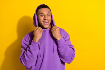 Photo of cheerful attractive young man in purple comfy hoodie go on walk during summer vacation isolated on yellow color background