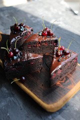 Dark chocolate cake with chocolate icing and seasonal cherries. Baking with alkalized cocoa with summer fruits and berries.