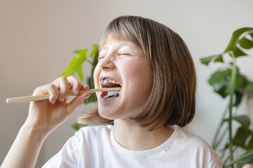 A girl brushes her teeth with an ecological toothbrush and bio toothpaste. Oral care. Caries...