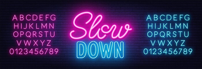 Slow Down neon lettering on brick wall background. - obrazy, fototapety, plakaty