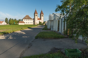 Fototapeta na wymiar Church of St. Peter and Paul and greenhouses on Reichenau Island, Baden-Wuerttemberg, Germany