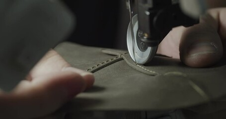Tailor works on sewing machine in private leather craftshop, making shoes in process. male seamstress sewing leather shoes in leather workshop in 4k
