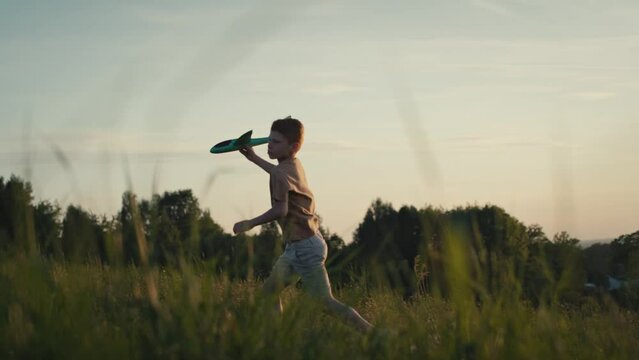 Little boy running with toy airplane at meadow. Shot with RED helium camera in 4K.  