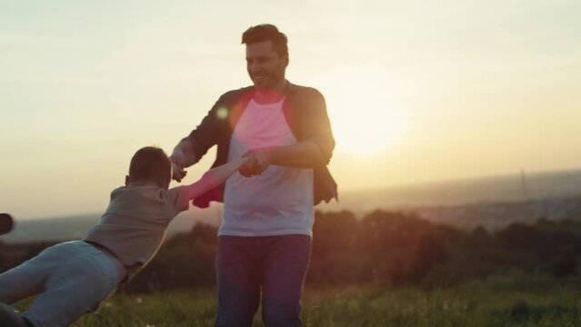 Dad playing with son at the meadow during the sunset. Shot with RED helium camera in 4K.  
