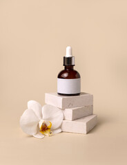 Naklejka premium Dropper glass bottle on stone near white orchid flowers on light yellow, Cosmetic Mockup