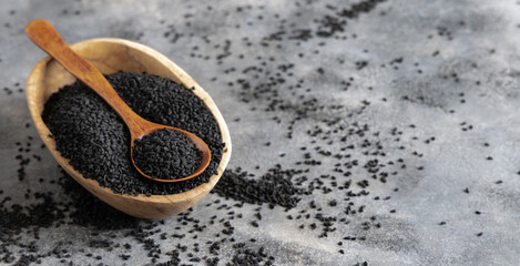 Indian spice Black cumin (nigella sativa or kalonji) seeds in bowl with spoon on wooden table close...