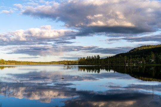 Midnight sun in northern Sweden with calm dark sky and reflections in mountain lake.