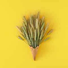 Creative layout made of wheat ears with ice cream cone on yellow background. Flat lay. Minimal food...