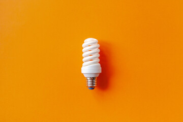 Energy saving light bulb on a orange background. Economical consumption of electricity. The concept...