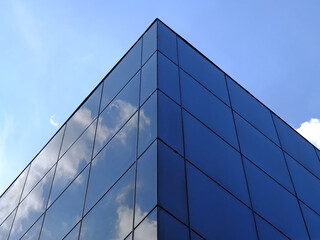 Fototapeta na wymiar Modern glass building against the blue sky. Bottom view of modern skyscraper in business district
