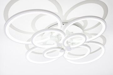 A modern chandelier with eight LED circles of different sizes.