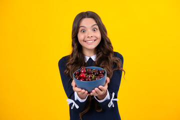 Teenager child girl hold sour cherry isolated on yellow background. Cherries for kids.