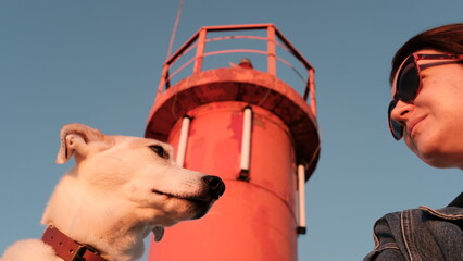 Girl and dog in front of the lighthouse at sunset