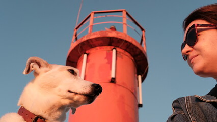 Girl and dog in front of the lighthouse at sunset