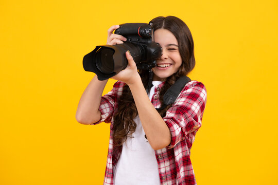 12, 13, 14 year old teen girl holding digital camera or DSLR over yellow background. Happy teenager, positive and smiling emotions of teen girl.