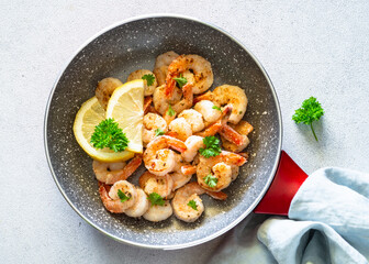 Frying shrimps with lemon in the frying pan. Top view image on white background.