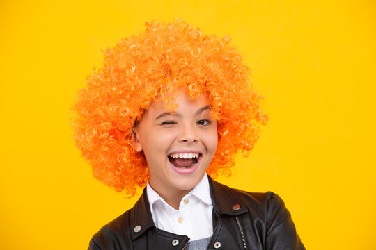 Funny face. Beautiful teenage girl in wig isolated on yellow. Funny clown wig.