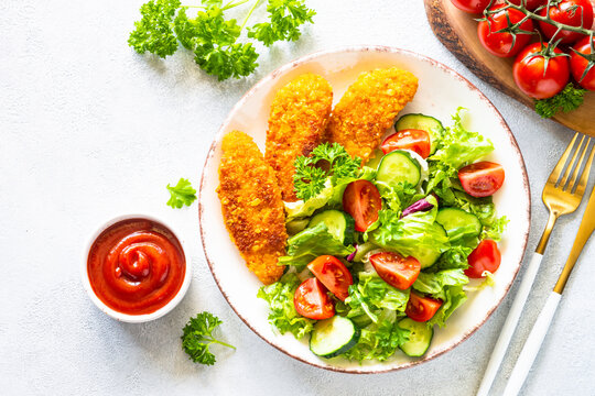 Chicken nuggets with fresh salad at white table. Top view image with copy space,