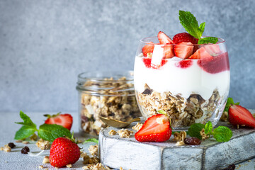 Parfait with cream or yogurt, jam and fresh strawberries in the glass jar. Close up.