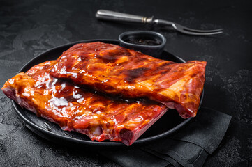 Ready for BBQ raw pork spare ribs with barbecue sauce. Black background. Top view