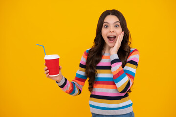Amazed teenager. Teenager girl holding a hot cup of coffee or tea. Child with takeaway cup on yellow background, morning energy drink beverage. Excited teen girl.