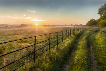 Fototapeta na wymiar Sunrise over rural fields fences and track in Norfolk UK