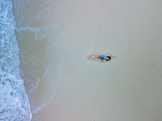 overhead view of woman in blue swimsuit at sea beach