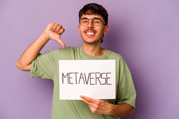 Young hispanic man holding meta verse placard isolated on purple background feels proud and self...