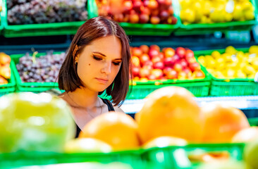 young woman in supermarket choosing grapefruits