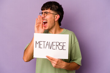 Young hispanic man holding meta verse placard isolated on purple background shouting and holding...