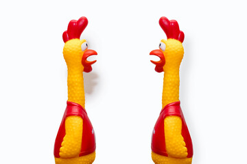 Two toy rubber toys in the form of a chicken on a white isolated background. Two toy chickens look at each other. A toy that makes a lot of noise. Funny artificial chickens that scream loudly