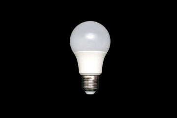 An energy-saving light bulb on a black background in the center of the image. Saving energy and finances. Electrical equipment and the evolution of light. disposable light bulb