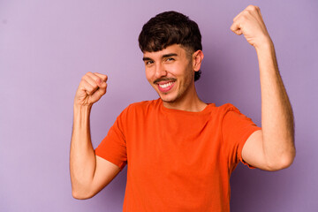 Fototapeta premium Young caucasian man isolated on purple background cheering carefree and excited. Victory concept.