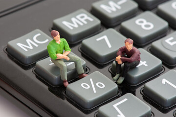 Deux figurines assises sur des touches de calculette juste à côté du symbole du pourcentage...