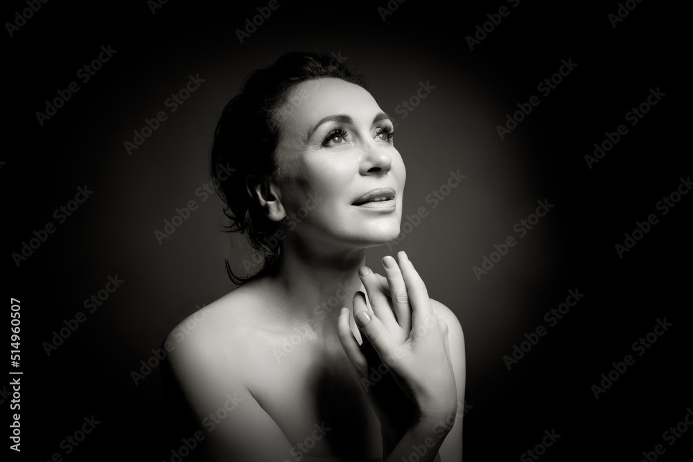 Wall mural Portrait of a sensual fifty -year -old woman on grey studio background. Monochrome shot.