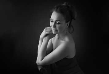 Portrait of a sensual fifty -year -old woman on grey studio background. Monochrome shot.