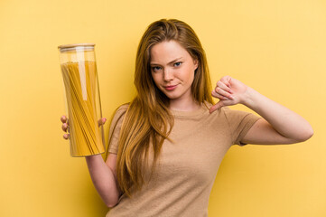 Young caucasian woman holding a spaghettis jar isolated on yellow background feels proud and self confident, example to follow.