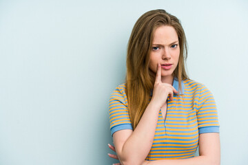 Young caucasian woman isolated on blue background looking sideways with doubtful and skeptical expression.