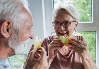 Senior couple eating melon at home - 514961593