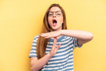 Young caucasian woman isolated on yellow background showing a timeout gesture.