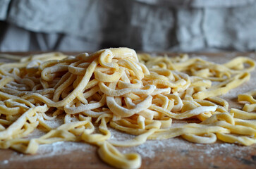 Homemade egg noodles sprinkled with flour on a wooden board