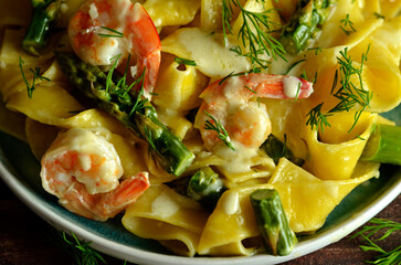 Pasta with shrimps and asparagus on a rustic plate