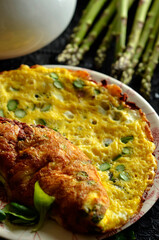 Egg omelette with asparagus on a dark background