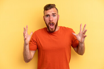 Young caucasian man isolated on yellow background screaming to the sky, looking up, frustrated.