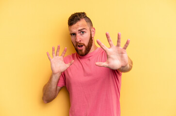 Young caucasian man isolated on yellow background being shocked due to an imminent danger